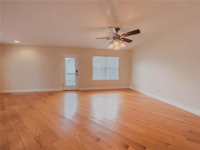 spare room featuring light wood-type flooring, a ceiling fan, and baseboards