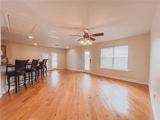 interior space with a healthy amount of sunlight, light wood finished floors, attic access, and baseboards