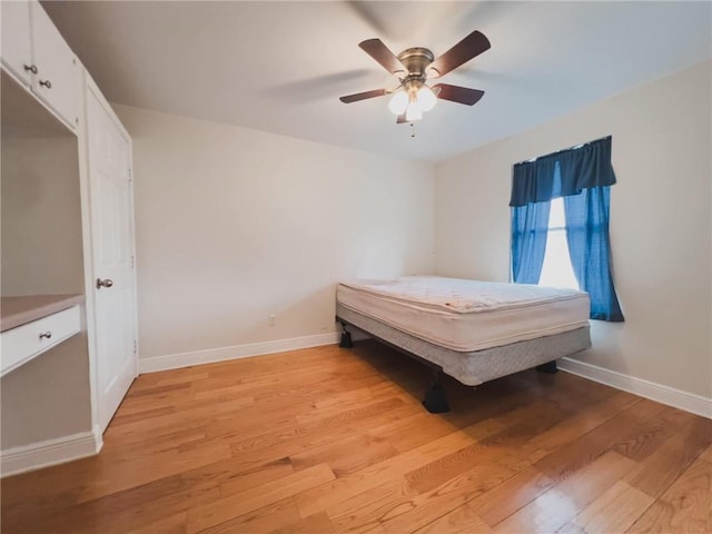 unfurnished bedroom featuring ceiling fan, light wood-type flooring, and baseboards