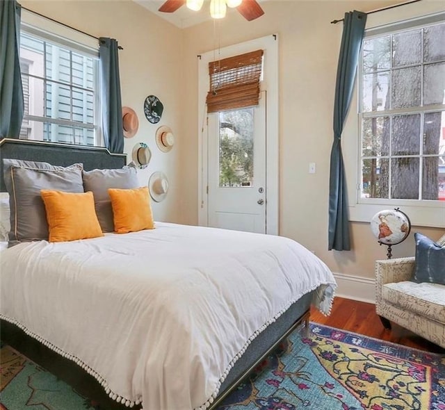 bedroom with ceiling fan, dark hardwood / wood-style flooring, and multiple windows