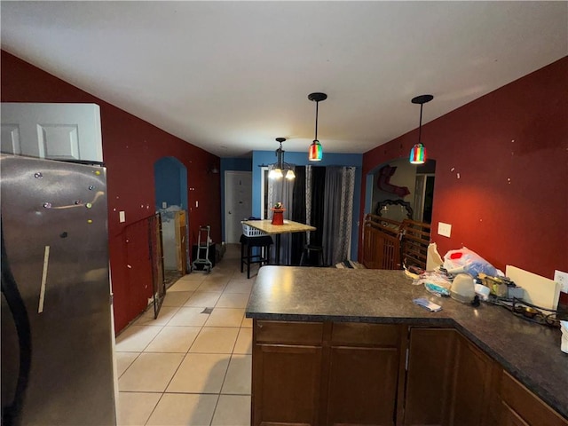 kitchen featuring stainless steel refrigerator, hanging light fixtures, and light tile patterned flooring