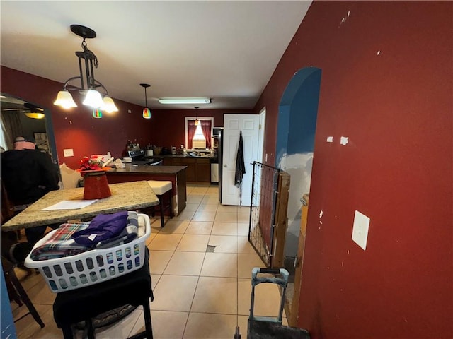 interior space featuring light tile patterned floors, hanging light fixtures, and stainless steel refrigerator