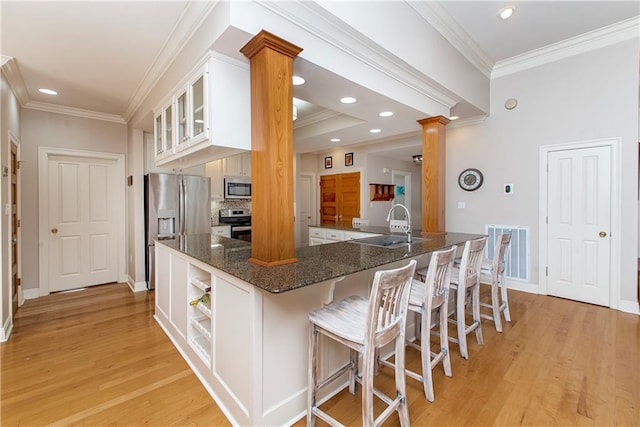 kitchen featuring kitchen peninsula, decorative columns, white cabinetry, and stainless steel appliances