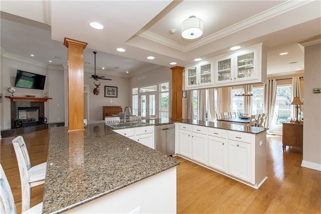 kitchen featuring kitchen peninsula, sink, dark stone countertops, dishwasher, and white cabinetry