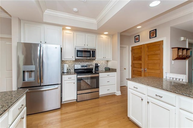 kitchen featuring appliances with stainless steel finishes, tasteful backsplash, white cabinetry, and dark stone counters