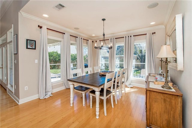 dining area with ornamental molding, light hardwood / wood-style flooring, a healthy amount of sunlight, and a notable chandelier