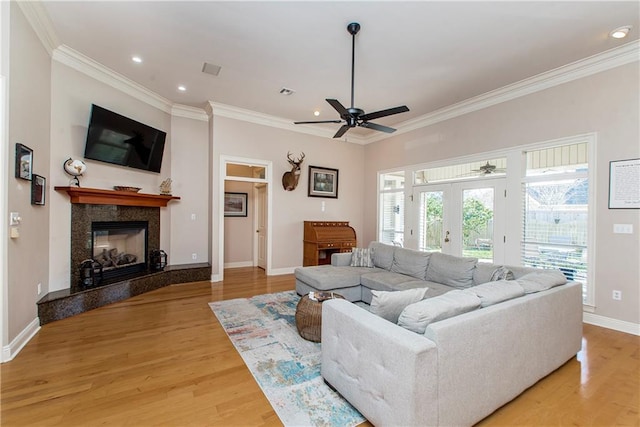 living room with a fireplace, light hardwood / wood-style floors, ceiling fan, and crown molding