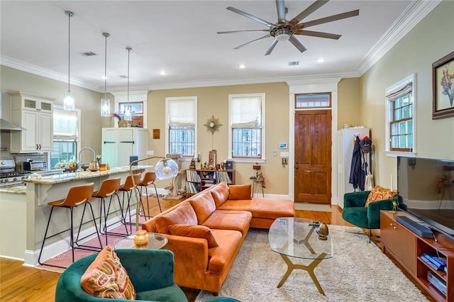 living room featuring light wood-type flooring, ceiling fan, and ornamental molding