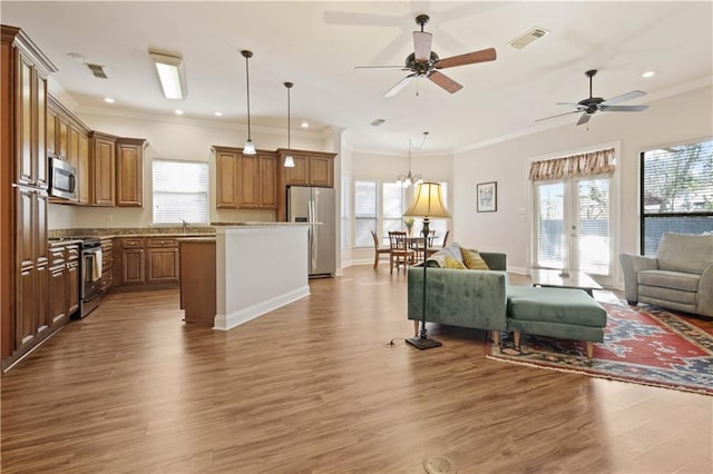 kitchen featuring a center island, crown molding, appliances with stainless steel finishes, decorative light fixtures, and light hardwood / wood-style floors