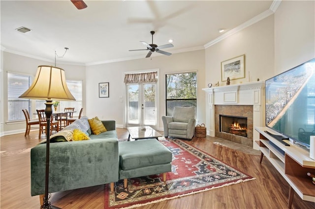 living room featuring crown molding, a tile fireplace, ceiling fan, and hardwood / wood-style flooring