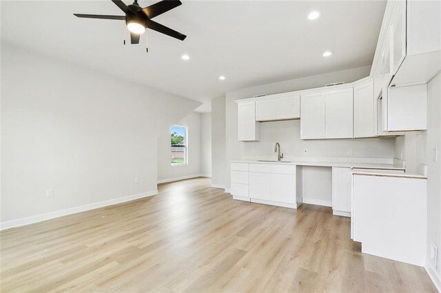 kitchen featuring a wealth of natural light, white cabinetry, sink, and light hardwood / wood-style flooring