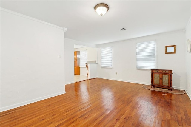 unfurnished living room featuring wood-type flooring and ornamental molding