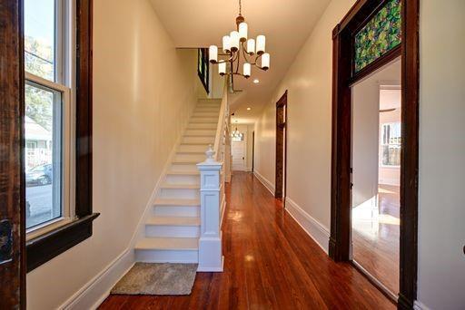 corridor with plenty of natural light, dark hardwood / wood-style floors, and a notable chandelier