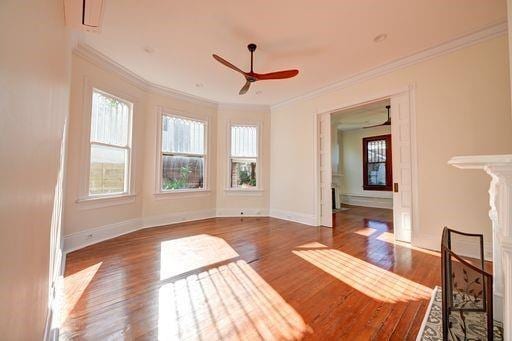 interior space featuring dark hardwood / wood-style flooring, ornamental molding, and ceiling fan