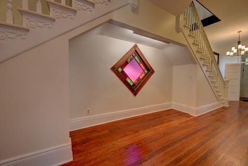 additional living space with an inviting chandelier and hardwood / wood-style floors