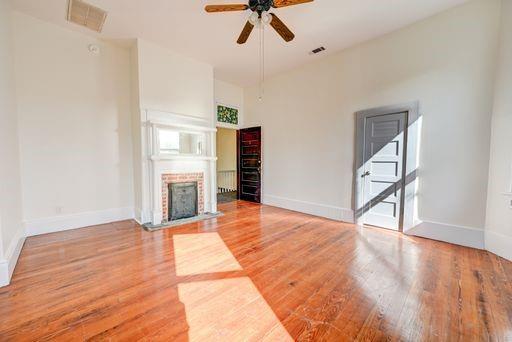 unfurnished living room with a brick fireplace, hardwood / wood-style flooring, and ceiling fan