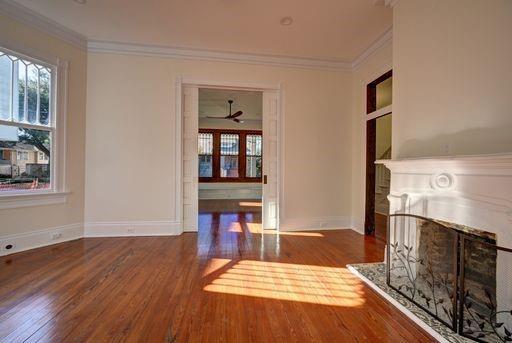 unfurnished living room featuring crown molding, dark hardwood / wood-style floors, and ceiling fan