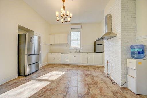 8241 Hickory St, New Orleans, LA 70118 - kitchen with freestanding refrigerator, wall chimney range hood, white dishwasher, a wall mounted AC, and a chandelier