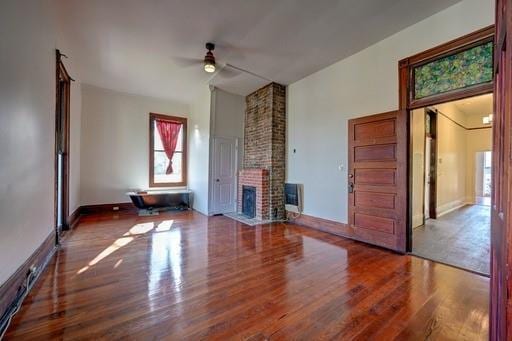 unfurnished living room with hardwood / wood-style flooring, a brick fireplace, and ceiling fan