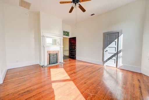 8241 Hickory St, New Orleans, LA 70118 - unfurnished living room featuring a ceiling fan, wood finished floors, and a fireplace