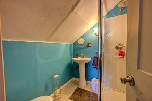 bathroom featuring toilet, vaulted ceiling, and a shower