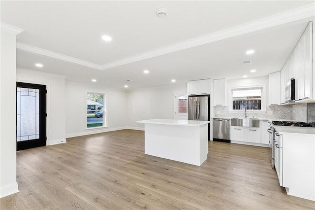 kitchen with white cabinetry, sink, backsplash, a kitchen island, and appliances with stainless steel finishes