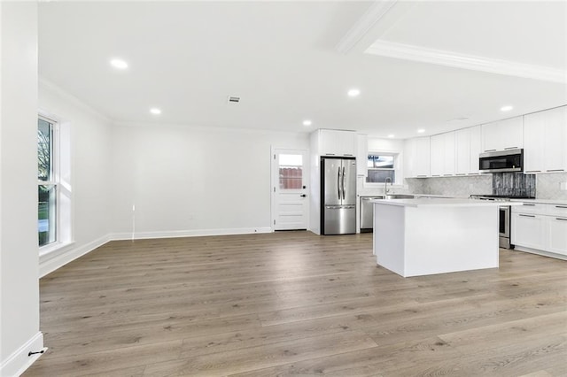 kitchen featuring a center island, appliances with stainless steel finishes, light hardwood / wood-style floors, white cabinets, and ornamental molding