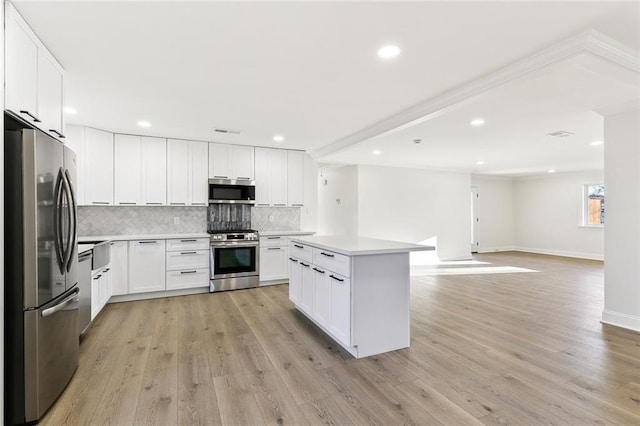 kitchen with white cabinetry, light hardwood / wood-style flooring, a kitchen island, and appliances with stainless steel finishes