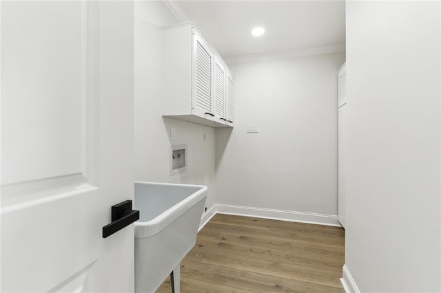 clothes washing area with cabinets, washer hookup, hardwood / wood-style flooring, and crown molding