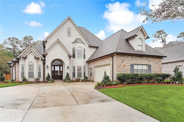 french country home featuring a garage, a front yard, and french doors