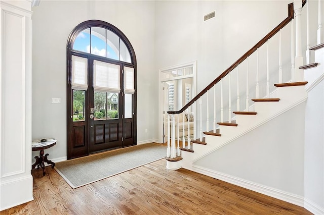 foyer with hardwood / wood-style floors and a towering ceiling