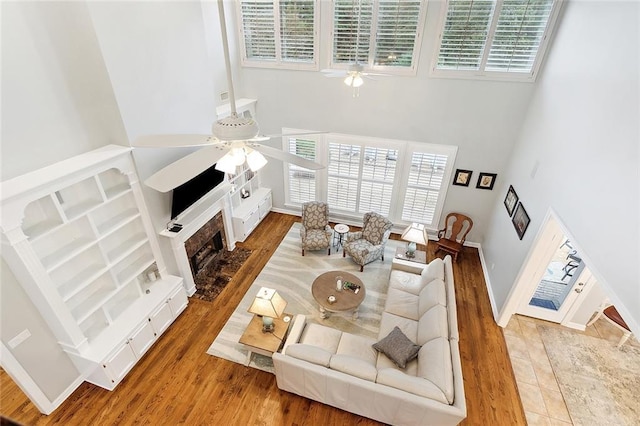 living room featuring ceiling fan, a towering ceiling, and hardwood / wood-style flooring