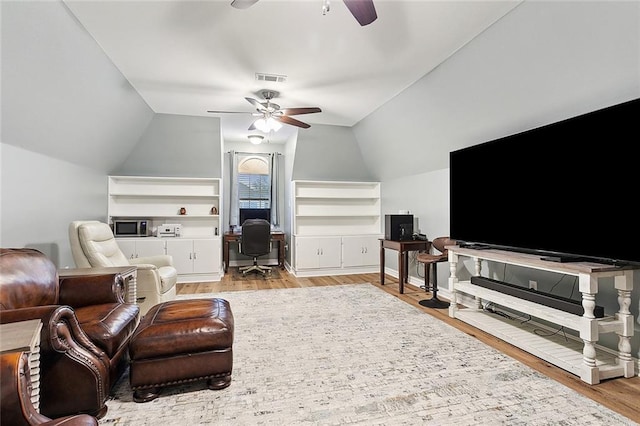 living room with light hardwood / wood-style flooring, vaulted ceiling, and ceiling fan