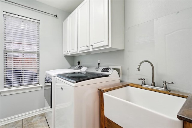 washroom with cabinets, light tile patterned floors, washer and clothes dryer, and sink