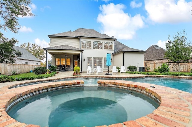 rear view of property featuring central AC unit, ceiling fan, a pool with hot tub, and a patio