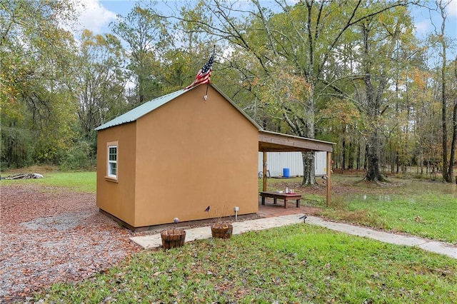 view of property exterior featuring a lawn, an outdoor structure, and a carport