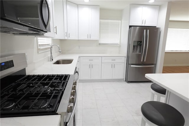 kitchen featuring white cabinets, sink, stainless steel appliances, and a wealth of natural light