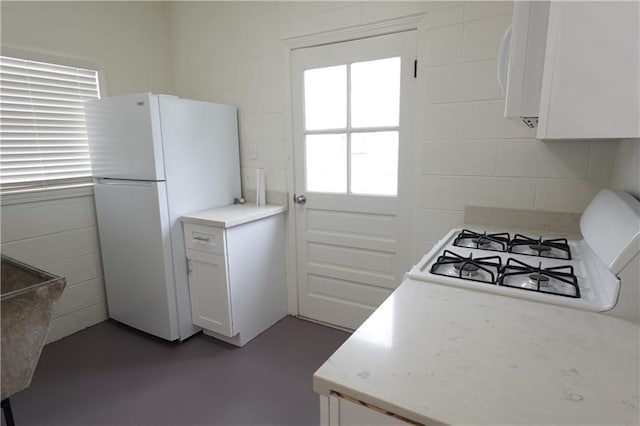 kitchen featuring stovetop, white refrigerator, and white cabinetry