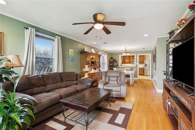 living room featuring ceiling fan with notable chandelier, ornamental molding, and light wood-type flooring