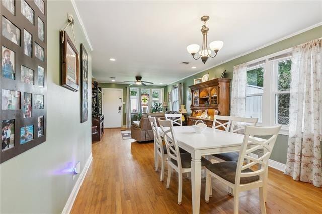 dining space featuring ornamental molding, ceiling fan with notable chandelier, and light hardwood / wood-style flooring