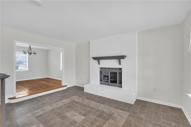 unfurnished living room with a brick fireplace and a notable chandelier