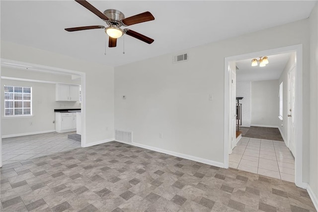 unfurnished living room featuring light tile patterned floors and ceiling fan with notable chandelier