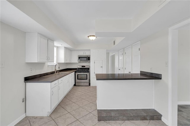 kitchen with sink, kitchen peninsula, appliances with stainless steel finishes, light tile patterned flooring, and white cabinetry