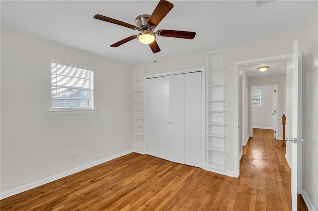 unfurnished bedroom with multiple windows, ceiling fan, a closet, and light hardwood / wood-style flooring