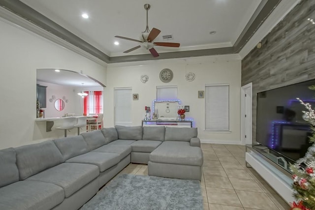 tiled living room with a tray ceiling, ceiling fan, and ornamental molding