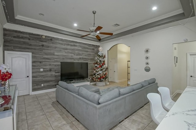 living room with light tile patterned floors, a tray ceiling, and crown molding