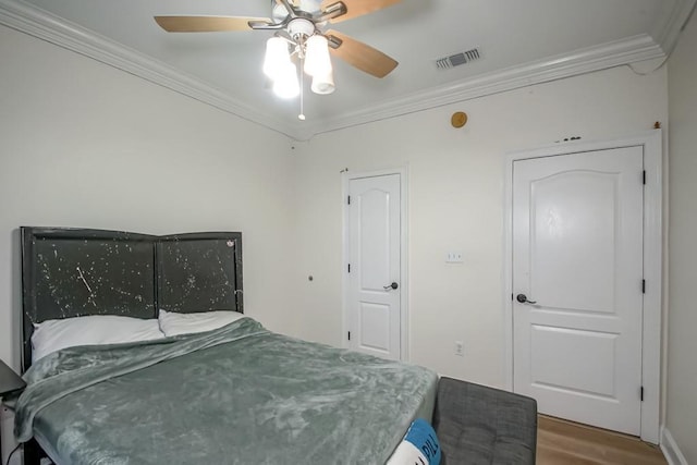 bedroom with hardwood / wood-style floors, ceiling fan, and ornamental molding