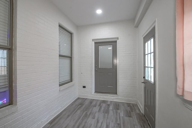 doorway to outside with dark hardwood / wood-style floors and brick wall