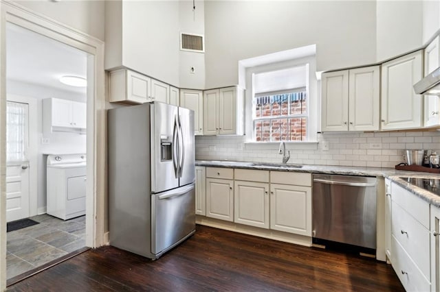 kitchen with washer / clothes dryer, light stone countertops, white cabinets, and appliances with stainless steel finishes