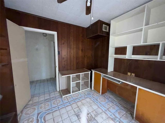 interior space with ceiling fan and wood walls